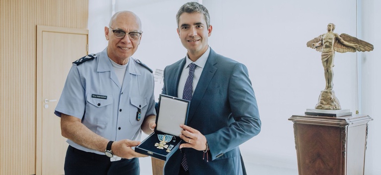 Foto mostrando diretor-geral da ANTT e comandante da Aeronáutica segurando a medalha