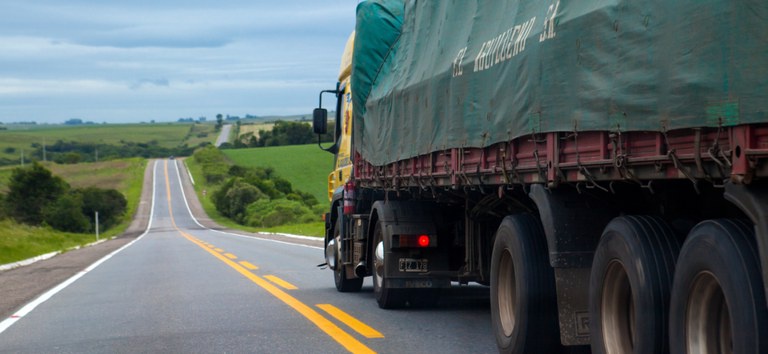 Foto mostrando caminhão fazendo transporte de cargas com frete em rodovia federal concedida