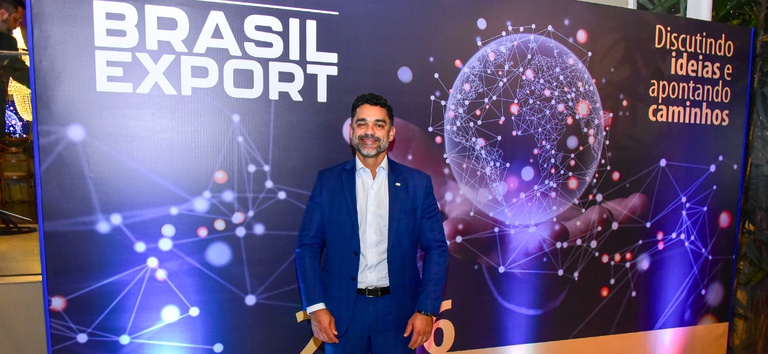 Foto mostrando o diretor da ANTT, Felipe Queiroz, em frente ao banner do Brasil Expor durante o evento