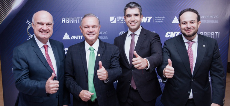 Foto mostrando o diretor-geral da ANTT, Guilherme Theo Sampaio, celebrando a premiação com um dos vencedores
