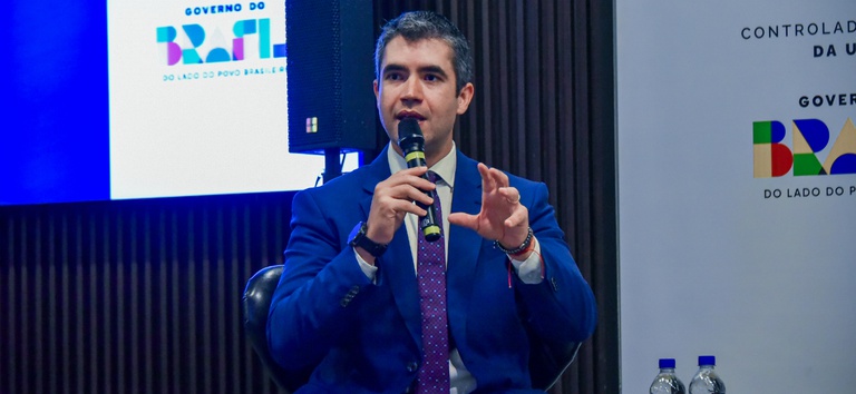 Foto do DG falando na mesa de abertura do evento