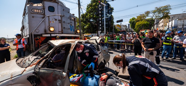 Foto mostrando o trem, equipes do SAMU, personagens e carros na simulação do acidente