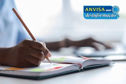 pessoa escrevendo no caderno com um lápis na mão