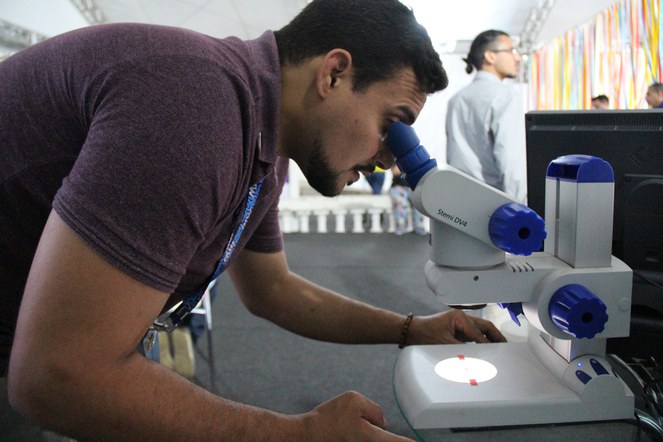 Vitor Galvão, Bolsista NIT Rio ajustando lupa para visualização do microchip pelos visitantes. Crédito: Tatiana Azzi