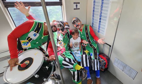 Arte-educadores ao lado de uma criança no trem