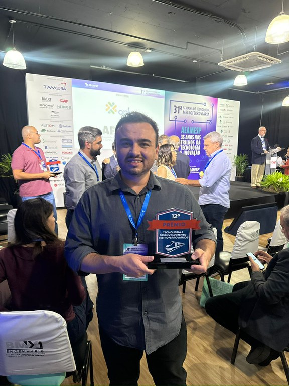 Empregado André Hozumi com troféu de finalista do 12º Prêmio de Tecnologia e Desenvolvimento Metroferroviários.