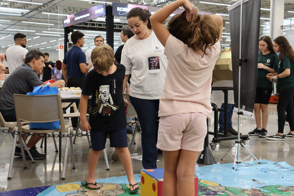 Cemaden no Science Days :Pesquisadora do Cemaden Educação orienta aluno do ensino fundamental no jogo educativo Trilha dos Riscos (Foto Cemaden Educação)