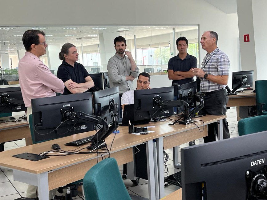 Equipe do BNDS em visita à Sala de Situação do Cemaden, conversa com tecnologista sobre o sistema de monitoramento.