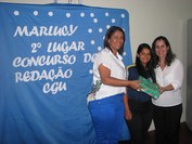 Marlucy (ao centro) recebe o prêmio das mãos da professora Edjany e da servidora Adila Maria, do NAP