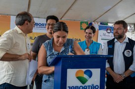 Na imagem mulher assina documento da casa própria 