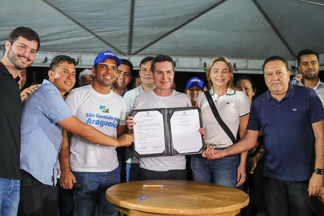 O ministro das Cidades junto à outras autoridades exibindo o documento do projeto