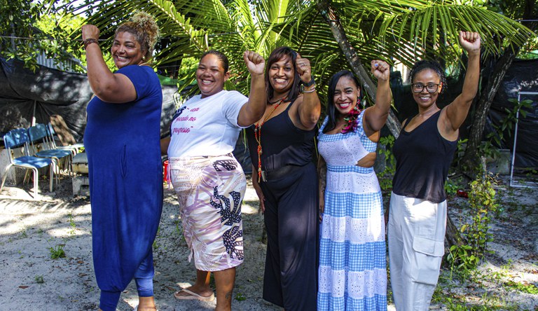 Na foto as cinco líderes comunitárias posam com mãos erguidas