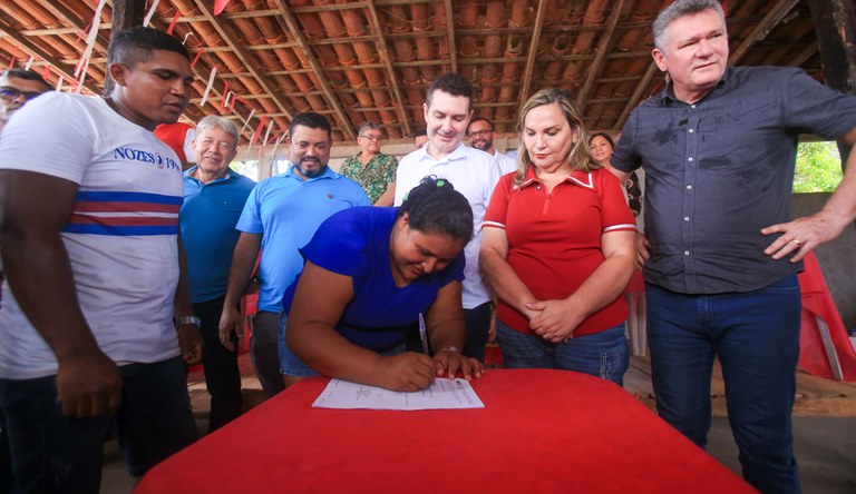 Mulher assinando documento de casa própria no Pará.