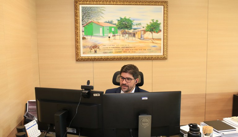 Na foto o secretário Nacional de Habitação, Augusto Rabelo, atrás de dois monitores de vídeo participando da abertura do evento online
