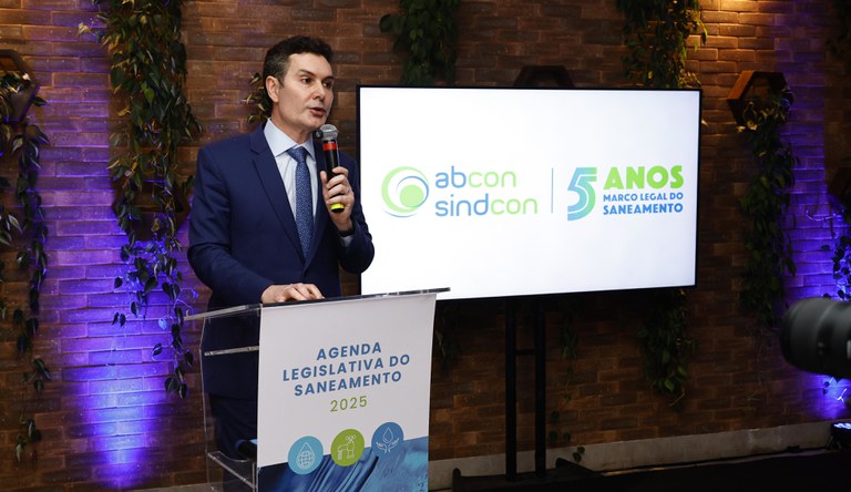 Homem discursa em evento da ABCON SINDCON sobre os 5 anos do Marco Legal do Saneamento e a Agenda Legislativa 2025.