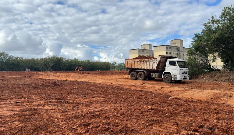 Na foto caminhão trabalha na terraplanagem de terreno para construção de unidades habitacionais do MCMV