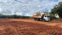 Na foto caminhão trabalha na terraplanagem de terreno para construção de unidades habitacionais do MCMV