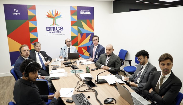 Na foto grupo de pessoas participando da reunião sentados a volta de uma mesa oval.