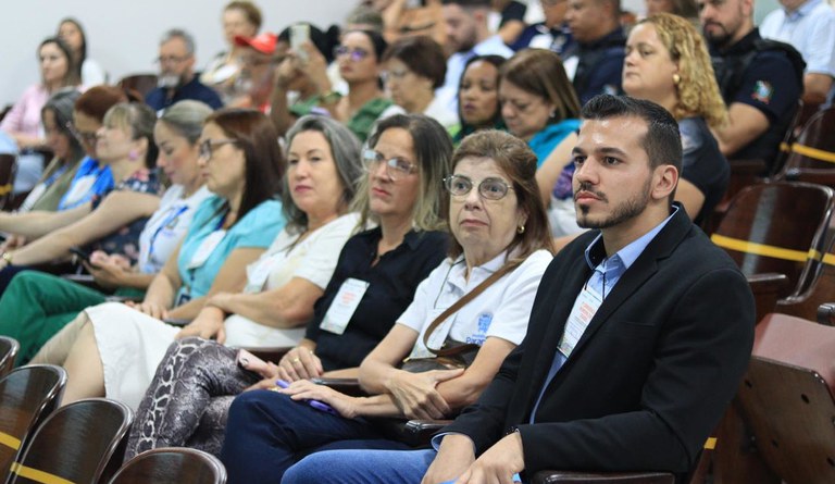 Grupo de pessoas sentadas num auditório assistindo uma palestra.