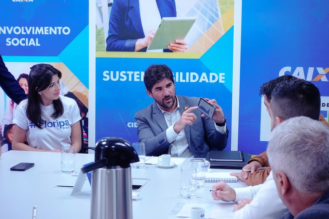 Na foto o secretário executivo mostra dados em um smartphone para os outros presentes