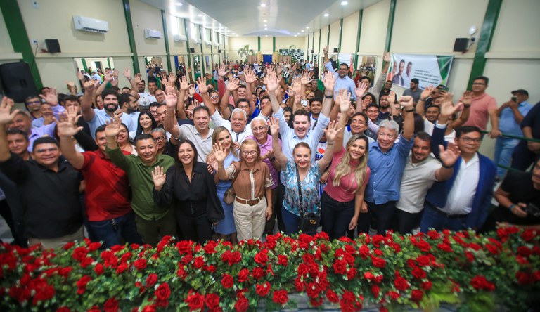 Grupo de pessoas em pé levantando as mãos e sorrindo.