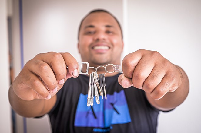 Homem negro segurando as chaves do seu apartamento. u