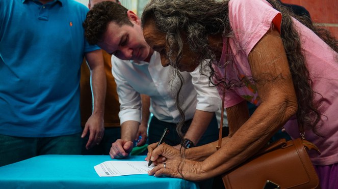 Mulher assinando contrato de casa própria no Pará. 