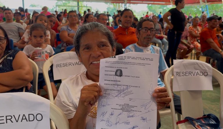 Mulher sorrindo segurando contrato da casa própria.