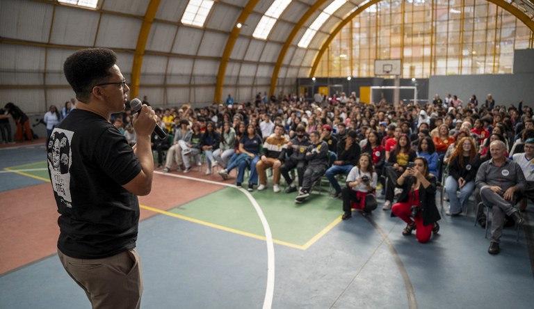 Homem com microfone falando com alunos de uma escola em Mauá, São Paulo.