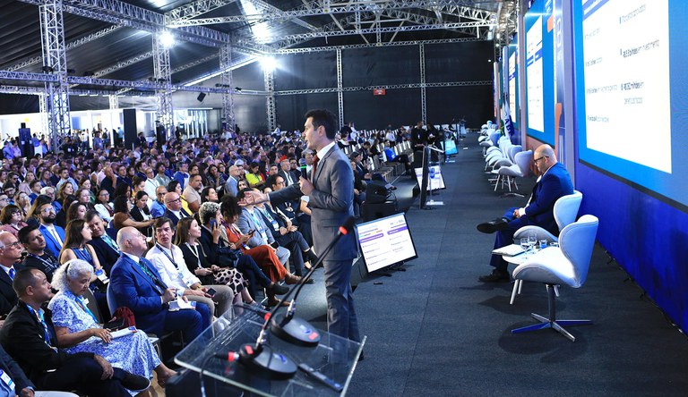 Homem falando para o público num auditório.