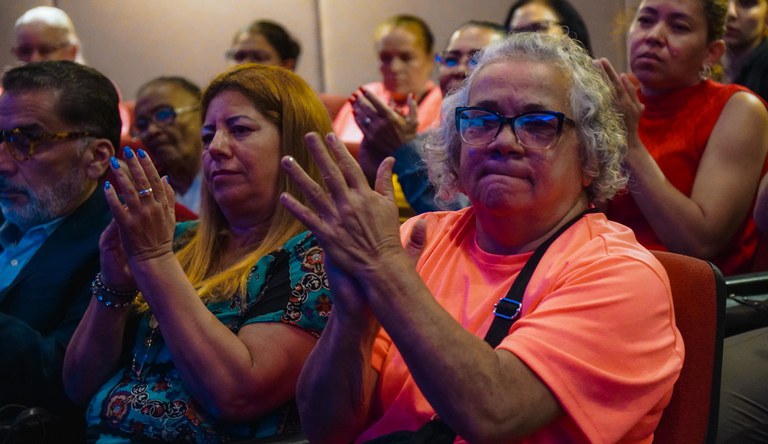 Grupo de pessoas sentadas num auditório.
