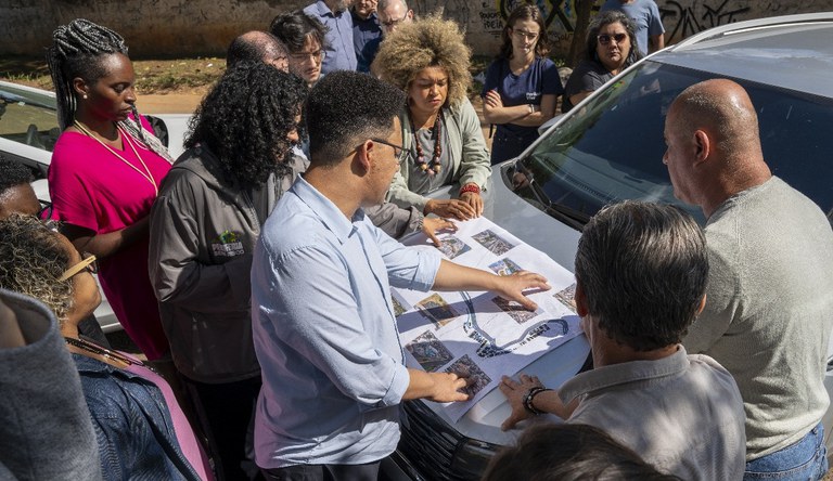 Grupo de pessoas conversando sobre o mapa de uma periferia.