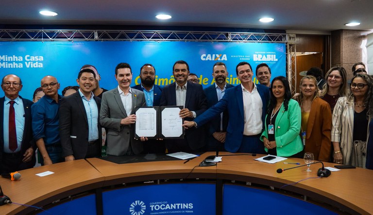 Pessoas numa reunidas comemorando a contratação de casas do programa MCMV.