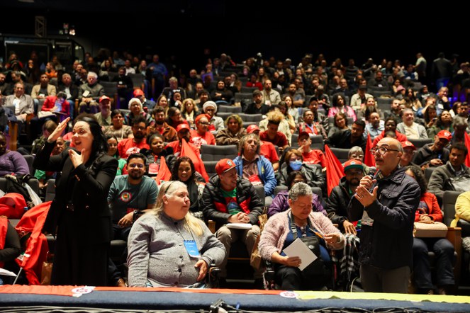 Pessoas sentadas num auditório. 