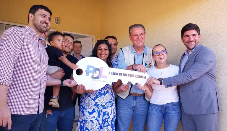 Na foto Augusto Rabelo entregando a chave simbólica a beneficiada e um grupo de pessoas.