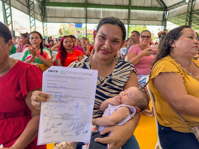 Na imagem mulher segura contrato de casa própria