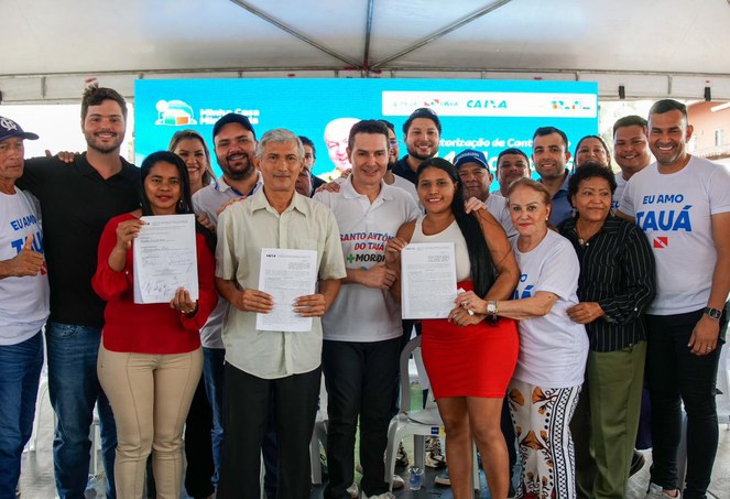 Beneficiários posam com contratos da casa própria