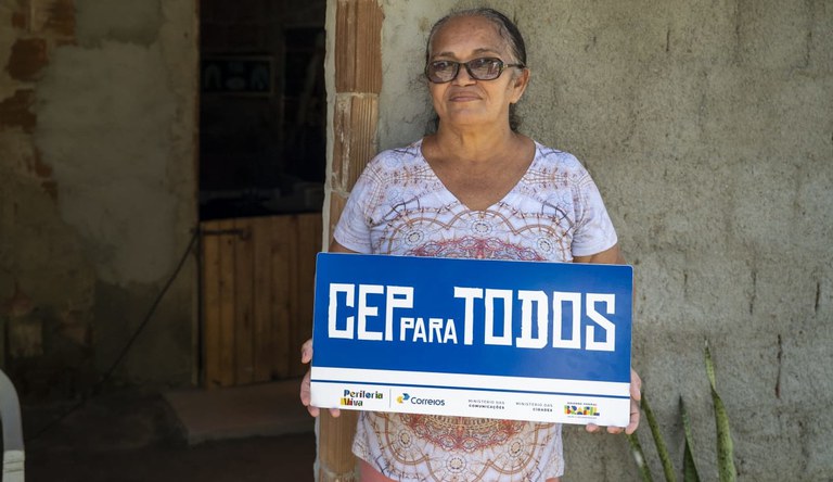Mulher segurando placa do programa Cep Para Todos