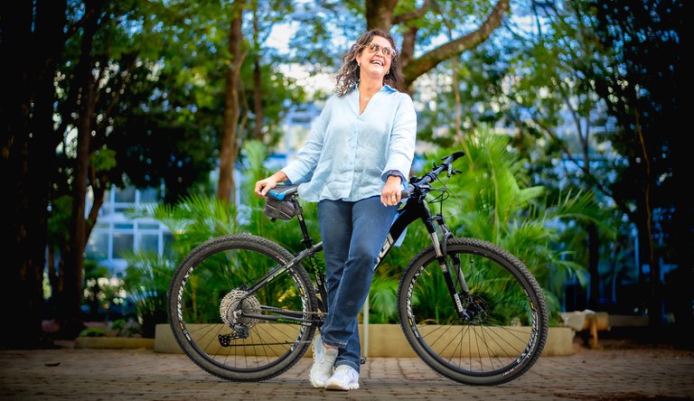 Mulher sorrindo em uma bicicleta em comemoração ao Dia do Ciclista