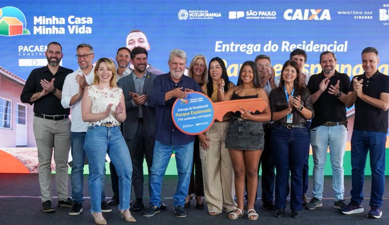 Mulher segurando chave simbólica da casa própria