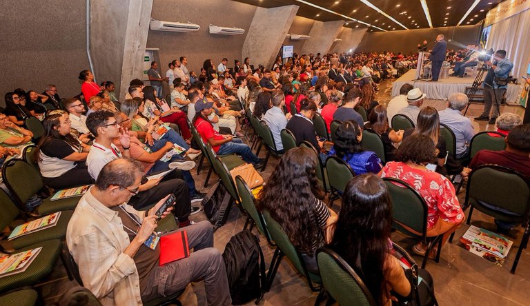 Na imagem plateia sentada ouvindo palestrante