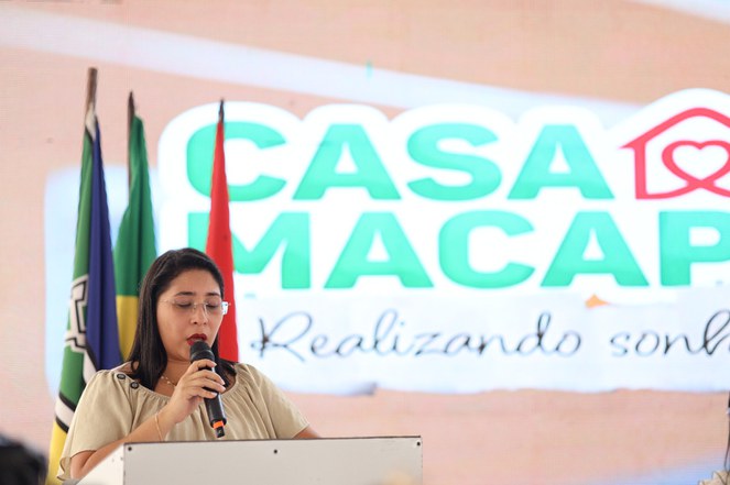 Na imagem mulher com microfone em evento do Minha Casa, Minha Vida 