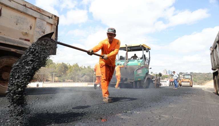 Na foto trabalhador da construção civil trabalhando em um asfaltamento