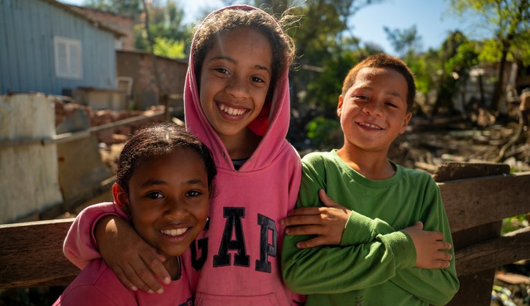 Na imagem três crianças sorrindo