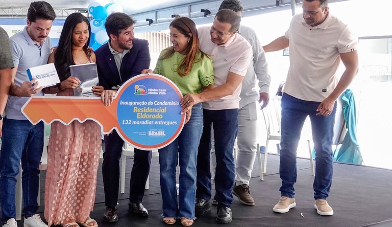 Mulher recebendo chave simbólica da casa pr´´opria