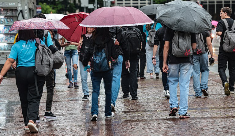 Pessoas andando na rua com guarda-chuva