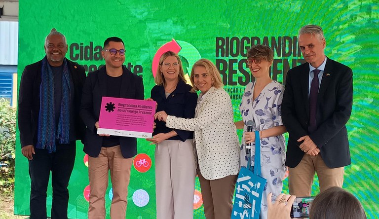 Na foto a equipe de Nova Friburgo em frente a um cartaz