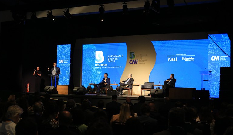 Homem falando para plateia em evento sobre meio ambiente e clima