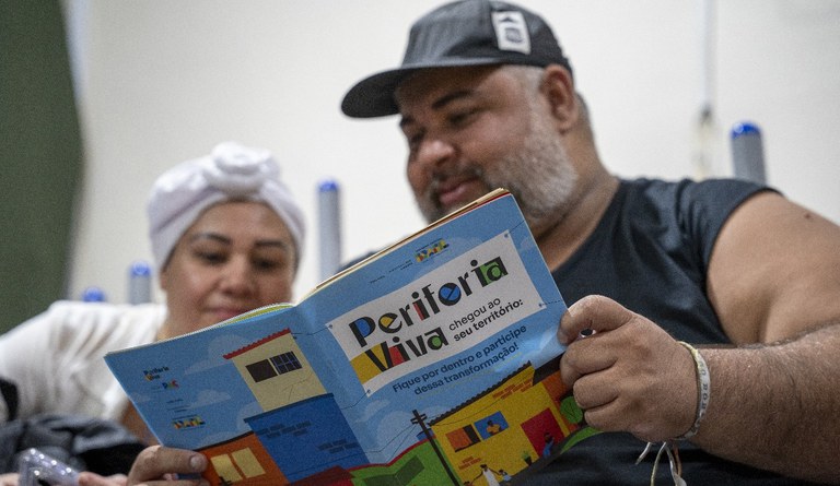 Homem e uma mulher olhando a revista do Periferia Viva