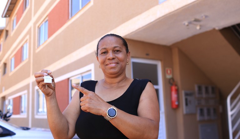 Mulher segurando chave de casa do programa Minha Casa, Minha Vida
